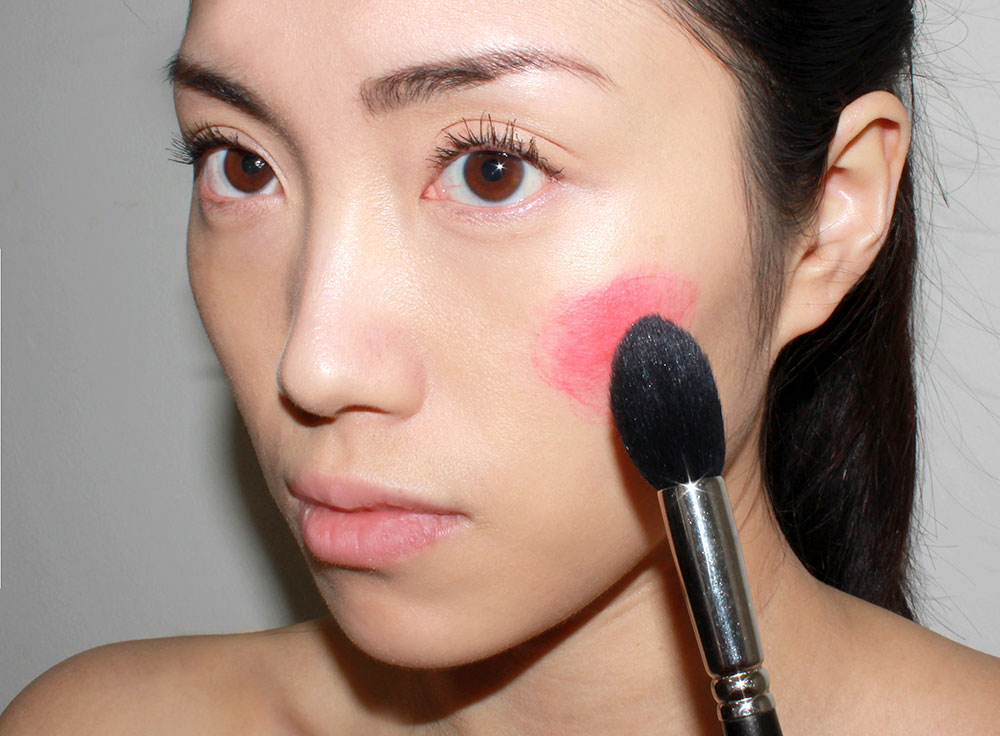 Blending cream blush on the cheeks